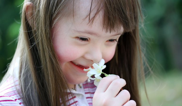 young girl smelling flower