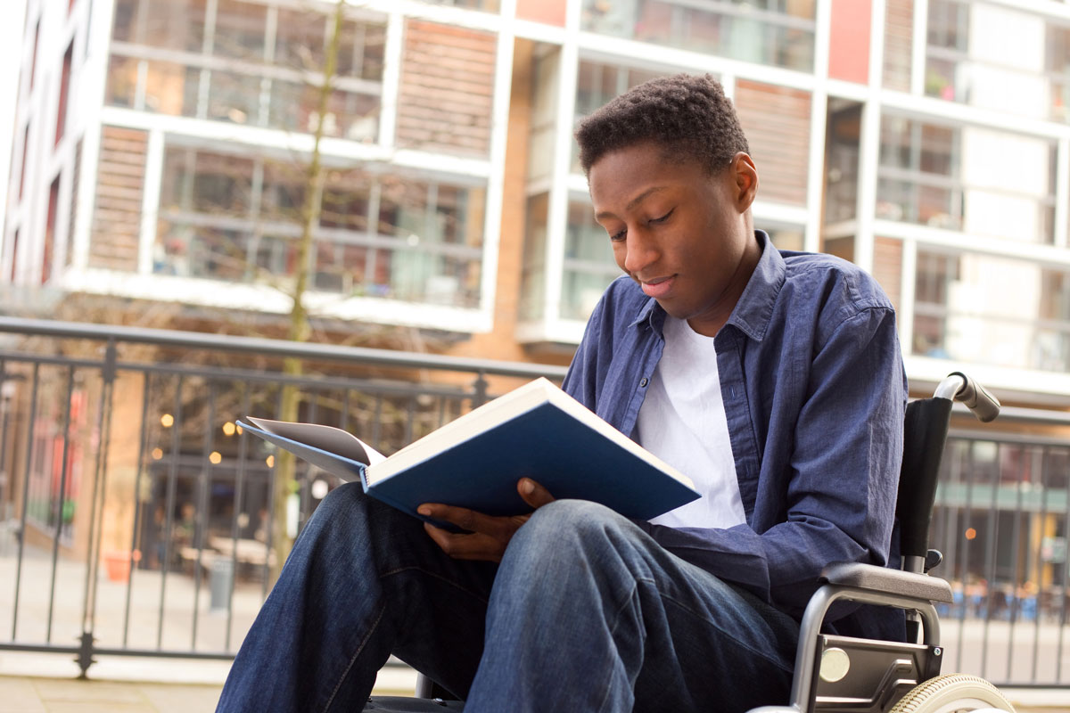 student outside with book, reading