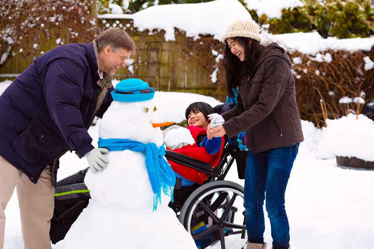family with special needs child playing with snowman